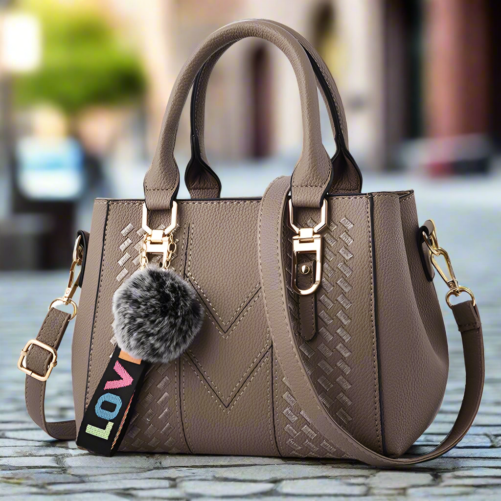“Embroidered leather handbag for women with hairball detail, stylish and versatile.”