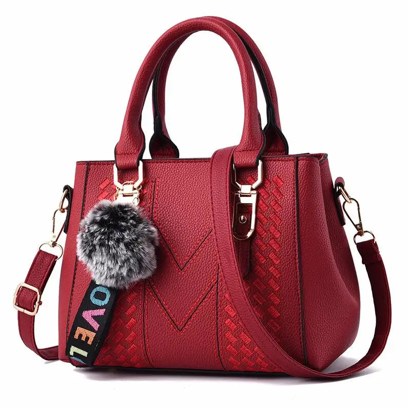 “Embroidered leather handbag for women with hairball detail, stylish and versatile.”