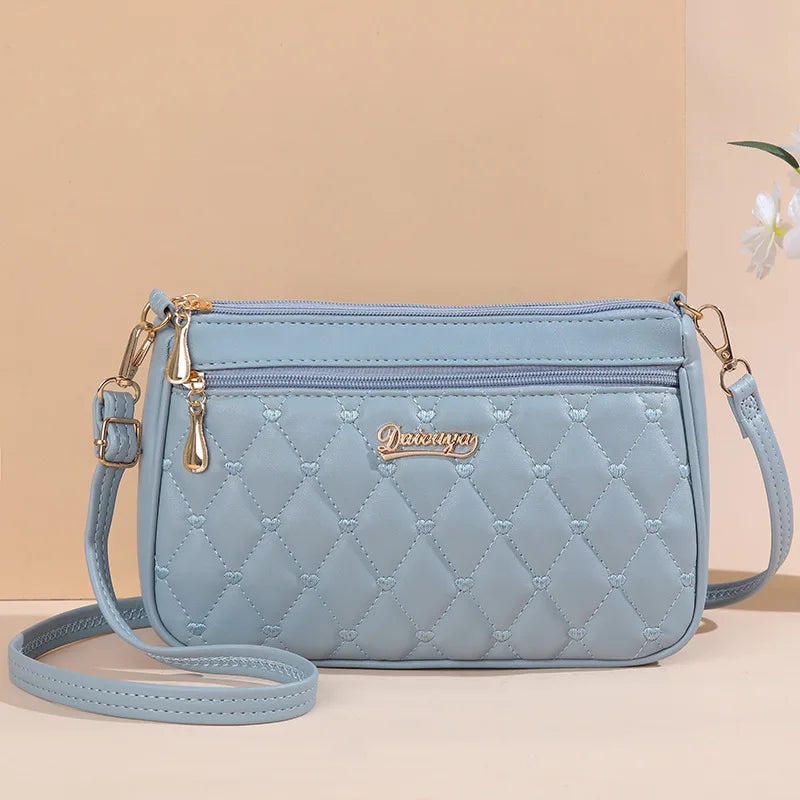 “Embroidered leather handbag for women with hairball detail, stylish and versatile.”