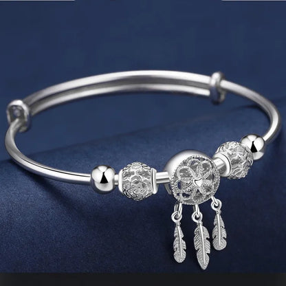 “Silver dreamcatcher tassel feather bracelet, lucky bead bangle, perfect for weddings.”